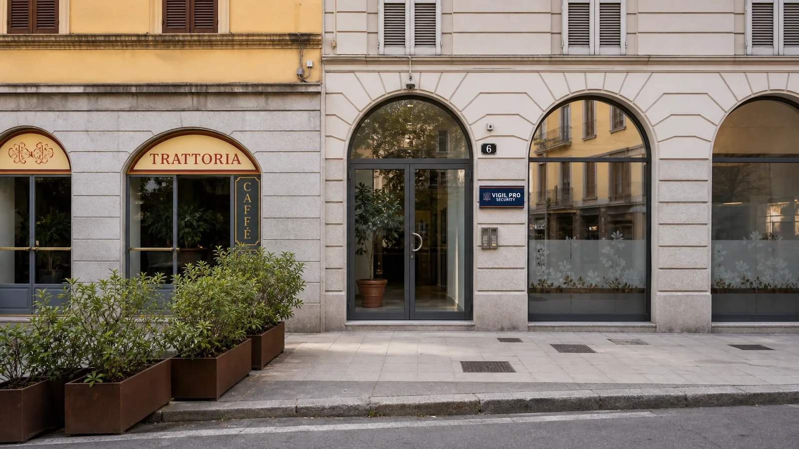 Facciata della sede Vigil Pro Security Srl in Piazza Santo Stefano 6 a Milano, ingresso vetrato con numero civico 6 e targa aziendale, edificio storico zona Isola accanto a una trattoria milanese